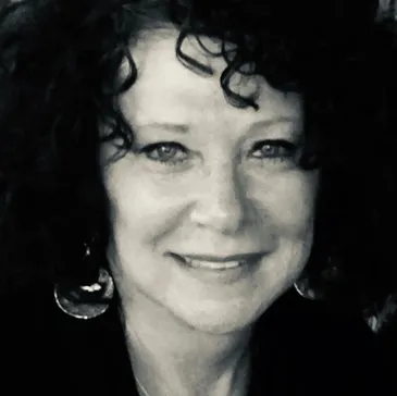 A black and white photo of a woman with curly hair.