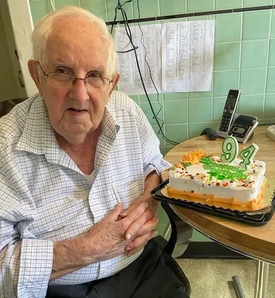 An older man sitting in front of a cake.