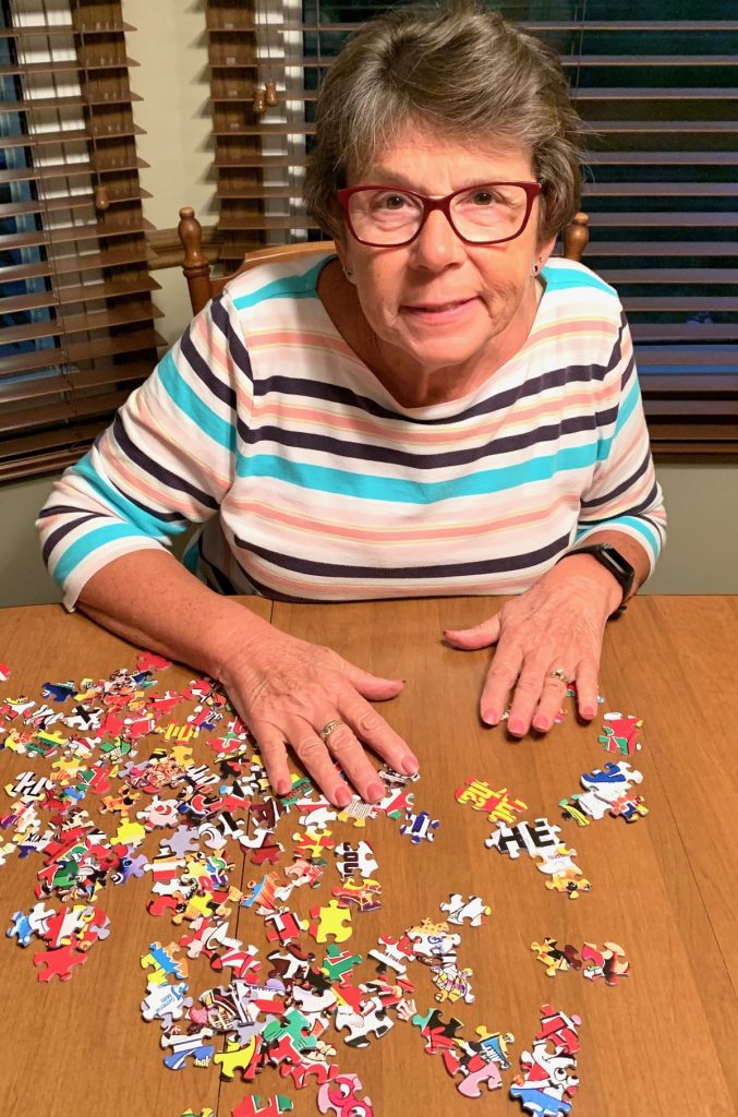 A woman sitting at the table with some puzzle pieces